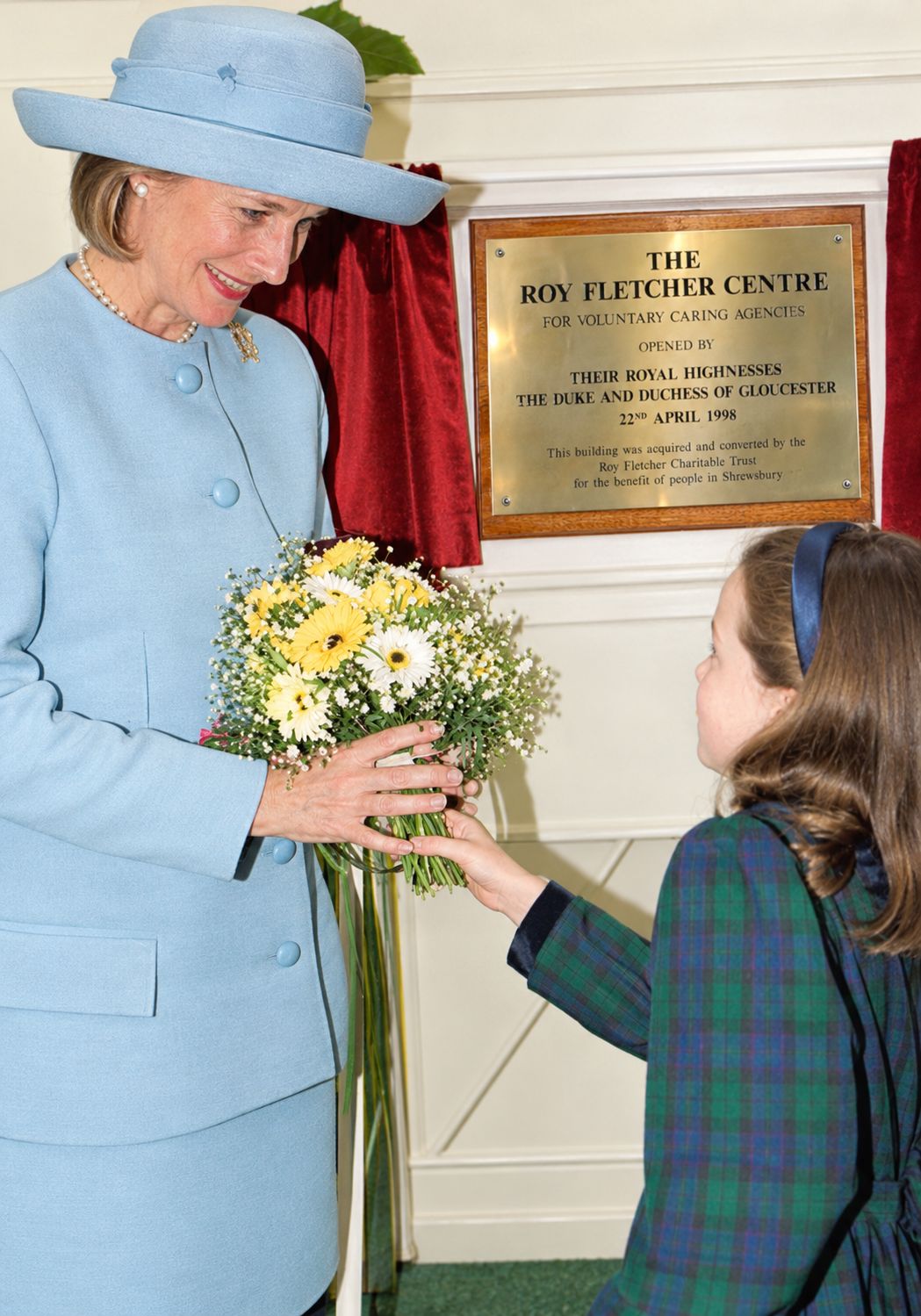Megan Cooper presenting a posy to the Duchess of Gloucester beside the newly unveiled plaque